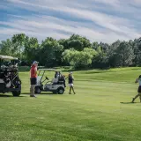 Women golfers on a sunny course, with carts and clubs ready. A charity golf tournament can last a full day, from morning to late afternoon.