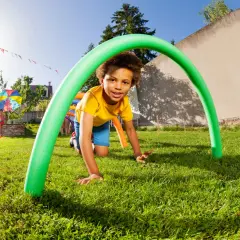 A boy crawls through a green pool noodle arch at a fun elementary school fall festival. Great ideas for outdoor games!