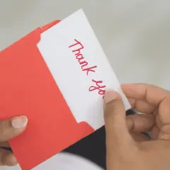 A handwritten "Thank You" card being pulled from a red envelope. A simple yet effective way to show how to reward volunteers.