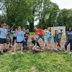 A diverse group of volunteers flexes their muscles, celebrating their hard work on a community service project.