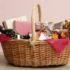 A wicker basket filled with gifts, including a bottle of wine, chocolates, and wrapped presents, perfect for cheap raffle prize ideas.