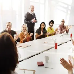 Diverse group applauds at a meeting, perhaps discussing advisory board vs board of directors roles.