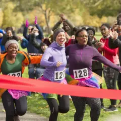 Runners cross the finish line at a fun charity event. This image shows how to start a charity event with enthusiastic participants and cheering crowds.