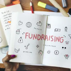 Open notebook with "FUNDRAISING" and icons for easy fundraisers. A to-do list and "Just Make the Best Things!" are visible.