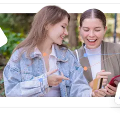 Two women excitedly look at a phone and credit card, suggesting easy transactions on giving day platforms.