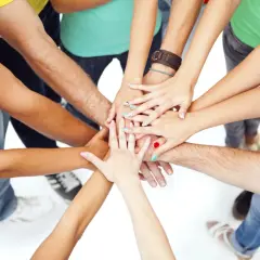 A diverse group of people with colorful nails and bracelets join hands in a circle, symbolizing unity and the spirit of a service trip.
