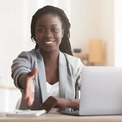 A smiling woman extends her hand for a handshake, embodying key volunteer coordination personal traits like approachability and enthusiasm.