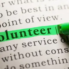 The word "Volunteer" is highlighted on a dictionary page, suggesting solutions to volunteering problems.