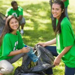 Students participate in community service projects, cleaning up a park and smiling as they collect trash.