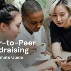 Three friends discuss peer-to-peer fundraising over coffee, looking at a smartphone.