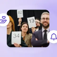People at an auction, holding up bid numbers like 34, 82, and 13, participating in a paddle raise.