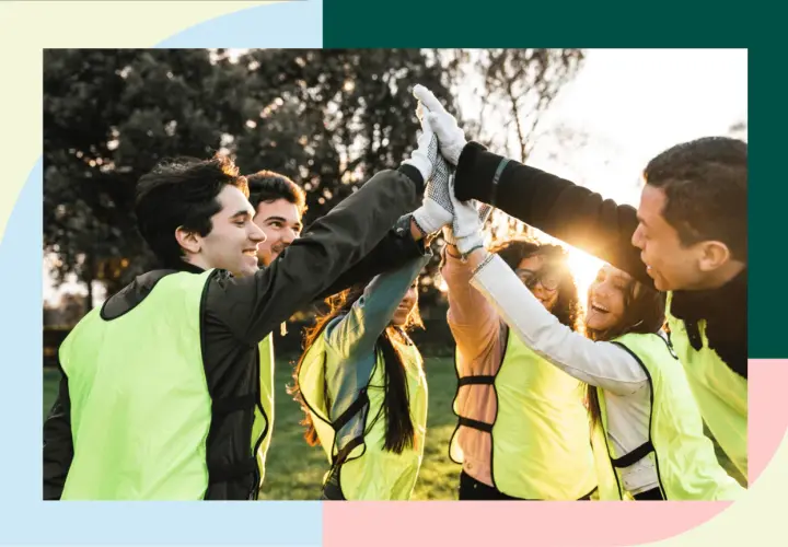 A diverse group of young people in bright vests high-five, celebrating their success in volunteer programs for youth.