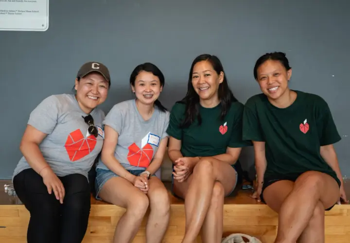 Four smiling women in matching t-shirts with a red heart logo, possibly participating in volunteer opportunities in NYC for college students.