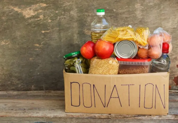A donation box filled with food items like pasta, apples, pickles, and eggs, perfect for fundraising ideas for homeless shelters.