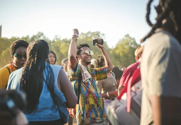 A man with sunglasses and a colorful shirt raises his fist in the air, capturing the energy of a dance-a-thon.
