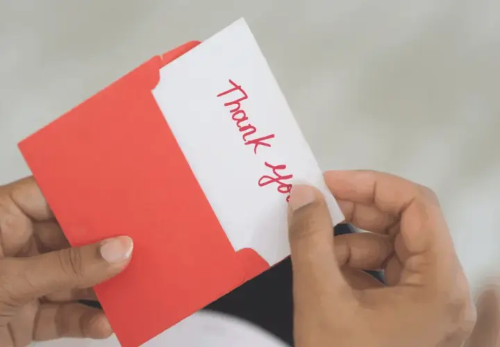 A handwritten "Thank You" card being pulled from a red envelope. A simple yet effective way to show how to reward volunteers.