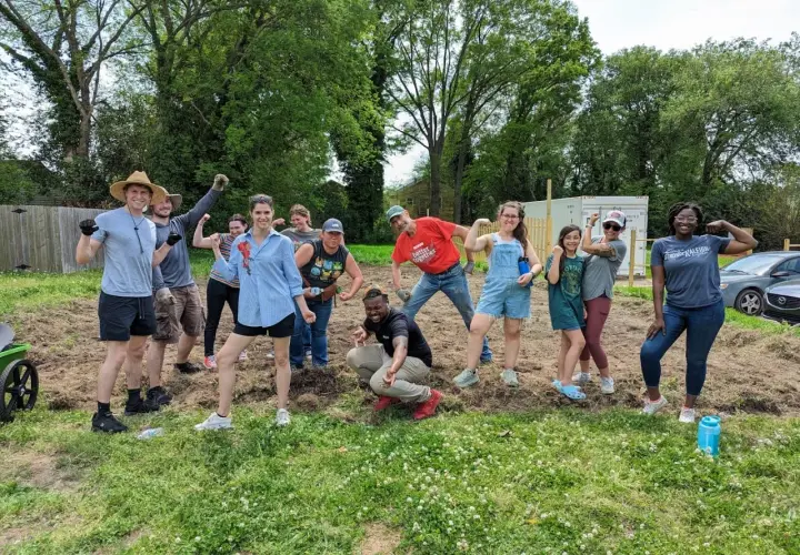 A diverse group of volunteers flexes their muscles, celebrating their hard work on a community service project.