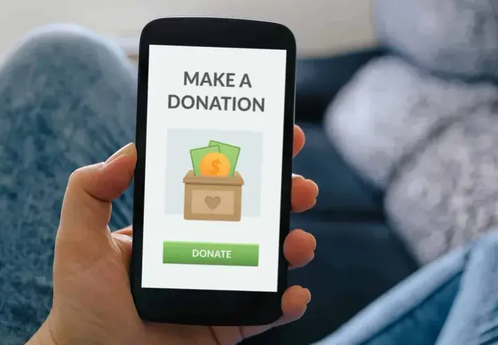 A person uses a donation app on their smartphone, showing a screen with a donation box icon and a "Donate" button.