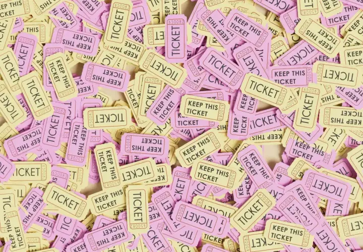 A pile of pink and yellow raffle tickets, some reading "KEEP THIS TICKET." This image might make you wonder, are raffles legal in Alabama?