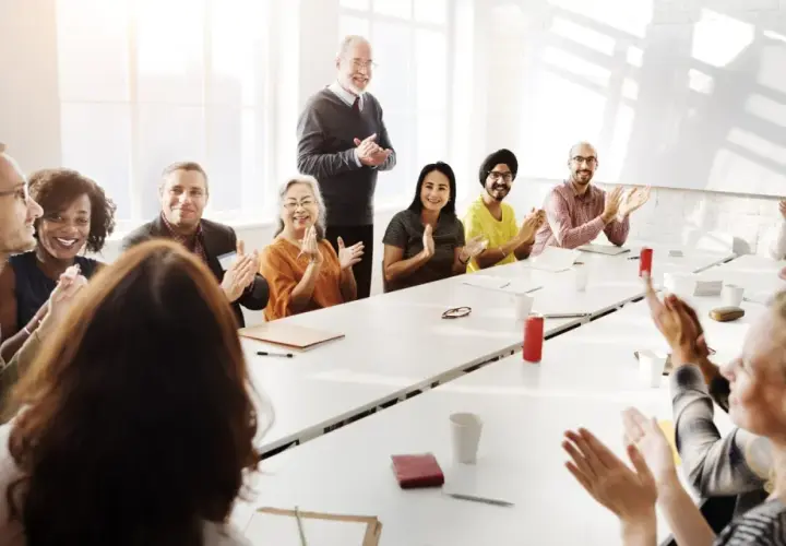 Diverse group applauds at a meeting, perhaps discussing advisory board vs board of directors roles.
