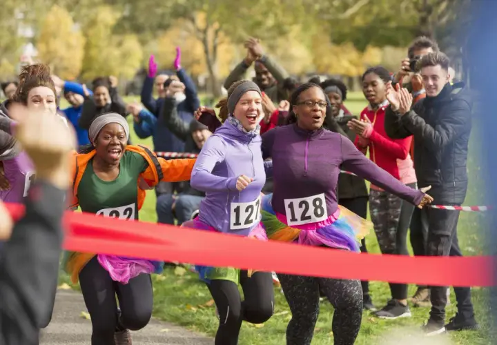 Runners cross the finish line at a fun charity event. This image shows how to start a charity event with enthusiastic participants and cheering crowds.