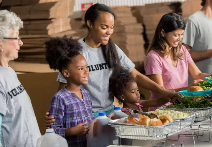 A student volunteer smiles as she helps serve food at a community event.
