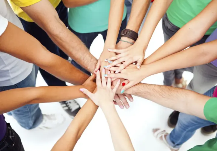 A diverse group of people with colorful nails and bracelets join hands in a circle, symbolizing unity and the spirit of a service trip.
