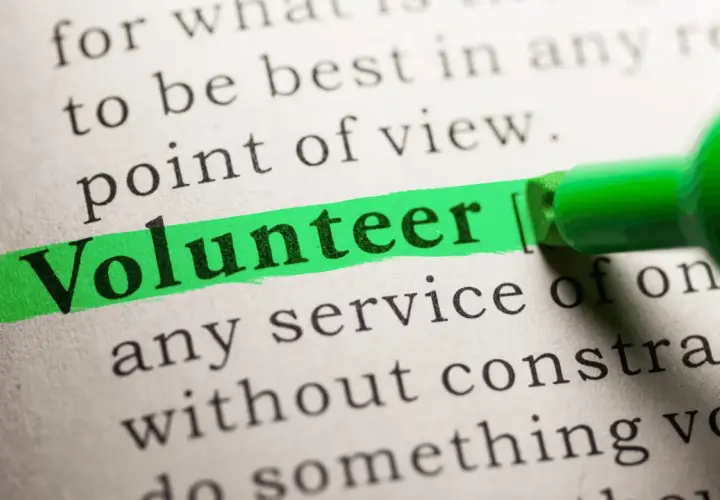 The word "Volunteer" is highlighted on a dictionary page, suggesting solutions to volunteering problems.