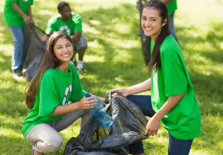 Students participate in community service projects, cleaning up a park and smiling as they collect trash.