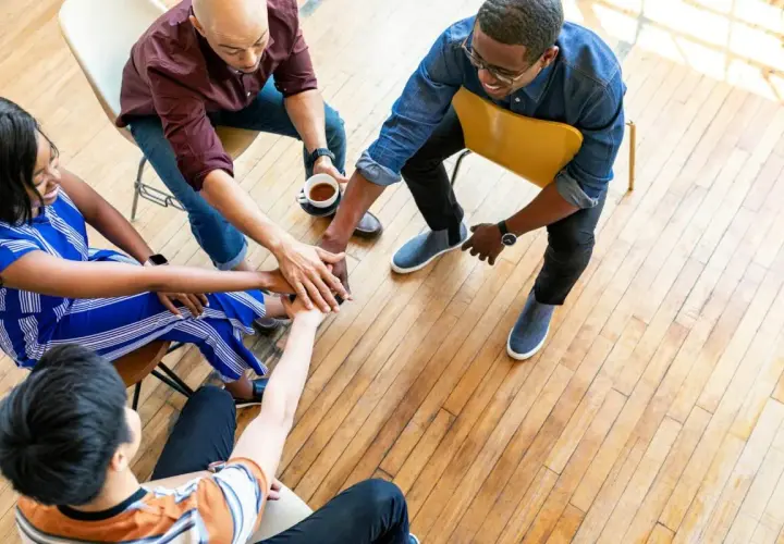A diverse small group joins hands in a circle, symbolizing unity and collaboration for successful fundraisers.