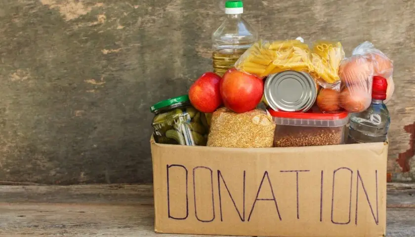 A donation box filled with food items like pasta, apples, pickles, and eggs, perfect for fundraising ideas for homeless shelters.