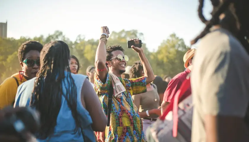 A man with sunglasses and a colorful shirt raises his fist in the air, capturing the energy of a dance-a-thon.