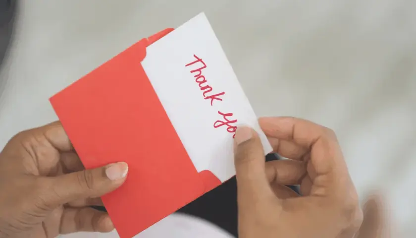 A handwritten "Thank You" card being pulled from a red envelope. A simple yet effective way to show how to reward volunteers.