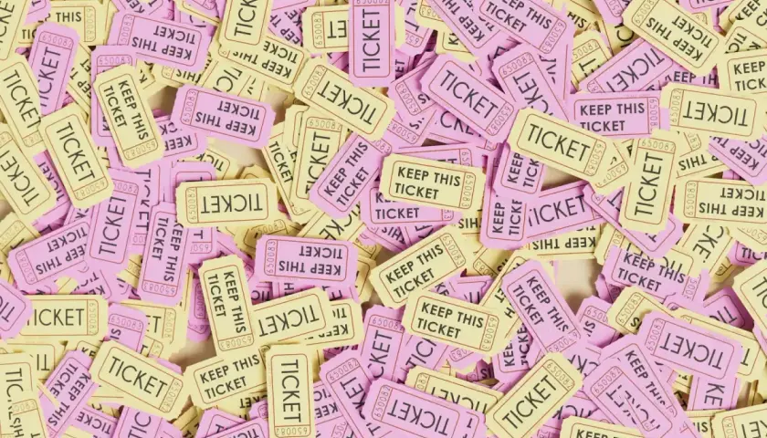 A pile of pink and yellow raffle tickets, some reading "KEEP THIS TICKET." This image might make you wonder, are raffles legal in Alabama?