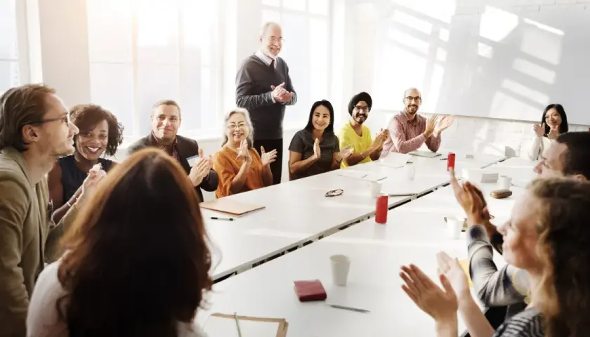 Diverse group applauds at a meeting, perhaps discussing advisory board vs board of directors roles.