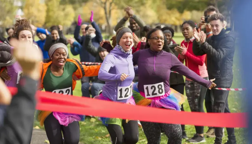Runners cross the finish line at a fun charity event. This image shows how to start a charity event with enthusiastic participants and cheering crowds.