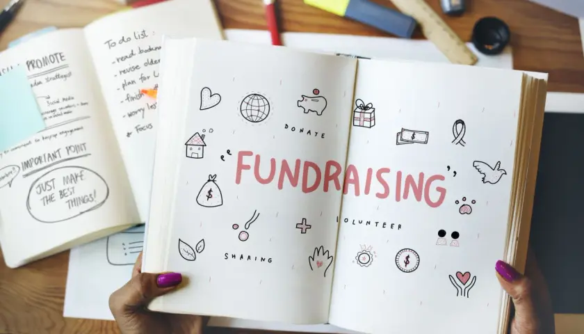 Open notebook with "FUNDRAISING" and icons for easy fundraisers. A to-do list and "Just Make the Best Things!" are visible.