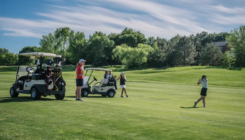 Women golfers on a sunny course, with carts and clubs ready. A charity golf tournament can last a full day, from morning to late afternoon.