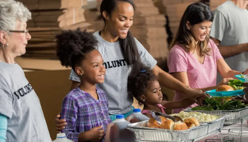 A student volunteer smiles as she helps serve food at a community event.
