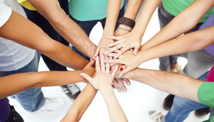 A diverse group of people with colorful nails and bracelets join hands in a circle, symbolizing unity and the spirit of a service trip.