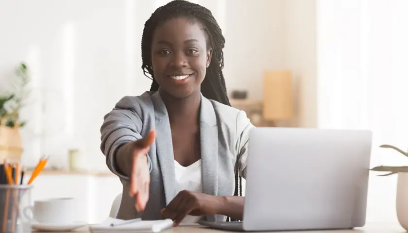 A smiling woman extends her hand for a handshake, embodying key volunteer coordination personal traits like approachability and enthusiasm.