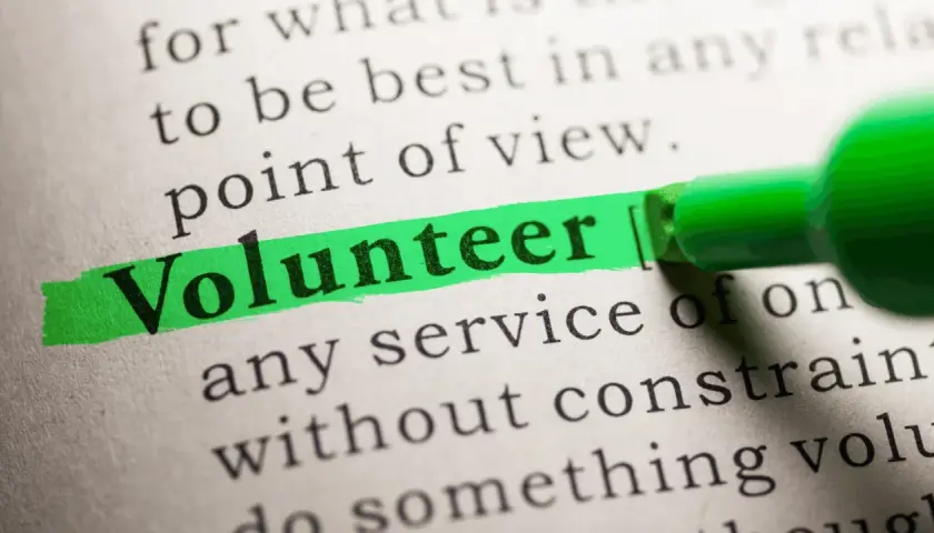 The word "Volunteer" is highlighted on a dictionary page, suggesting solutions to volunteering problems.