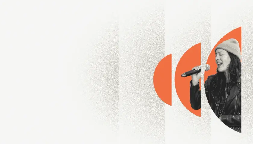 A woman sings into a microphone, her eyes closed in passion. Explore music volunteer opportunities and share your voice.