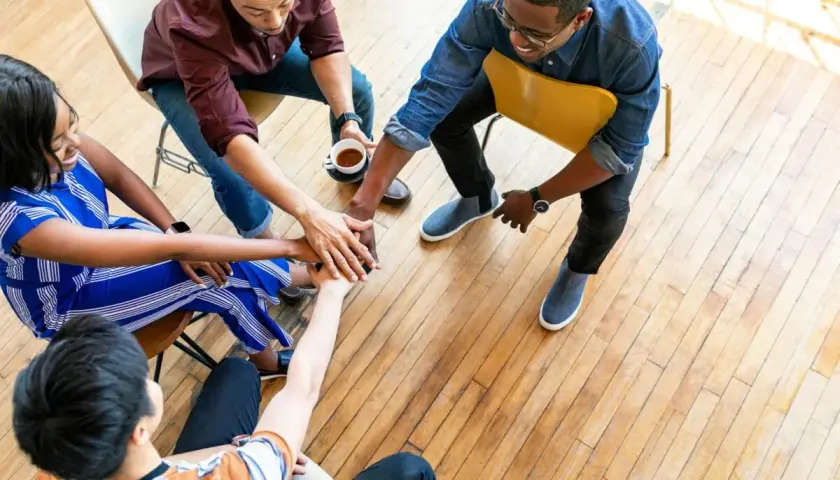 A diverse small group joins hands in a circle, symbolizing unity and collaboration for successful fundraisers.