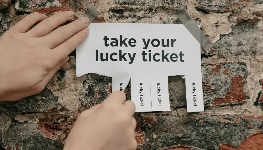 Hands tear off "lucky ticket" strips from a poster on a brick wall, offering great raffle ideas.