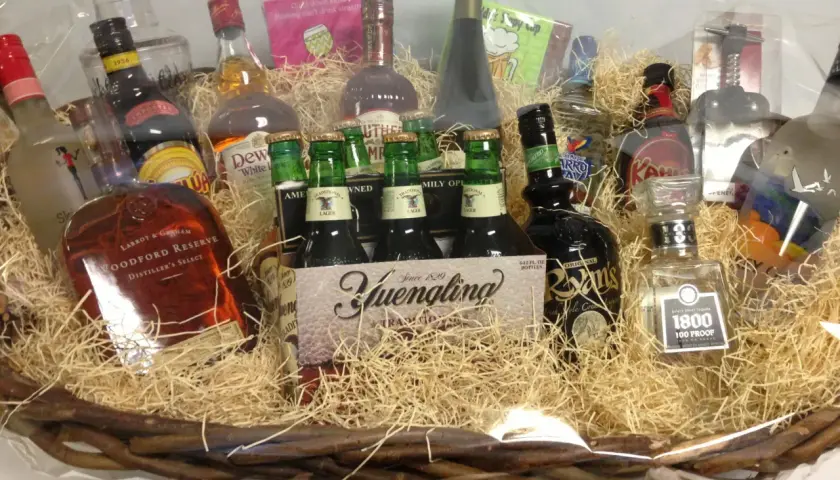 A festive basket filled with spirits and beer, perfect for unique charity gift basket ideas. Includes Woodford Reserve, Yuengling, and 1800 Tequila.