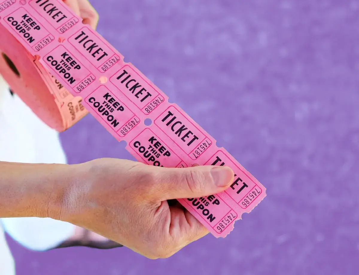 Hands hold a roll of pink raffle tickets, ready to be torn off for big ticket raffle items.