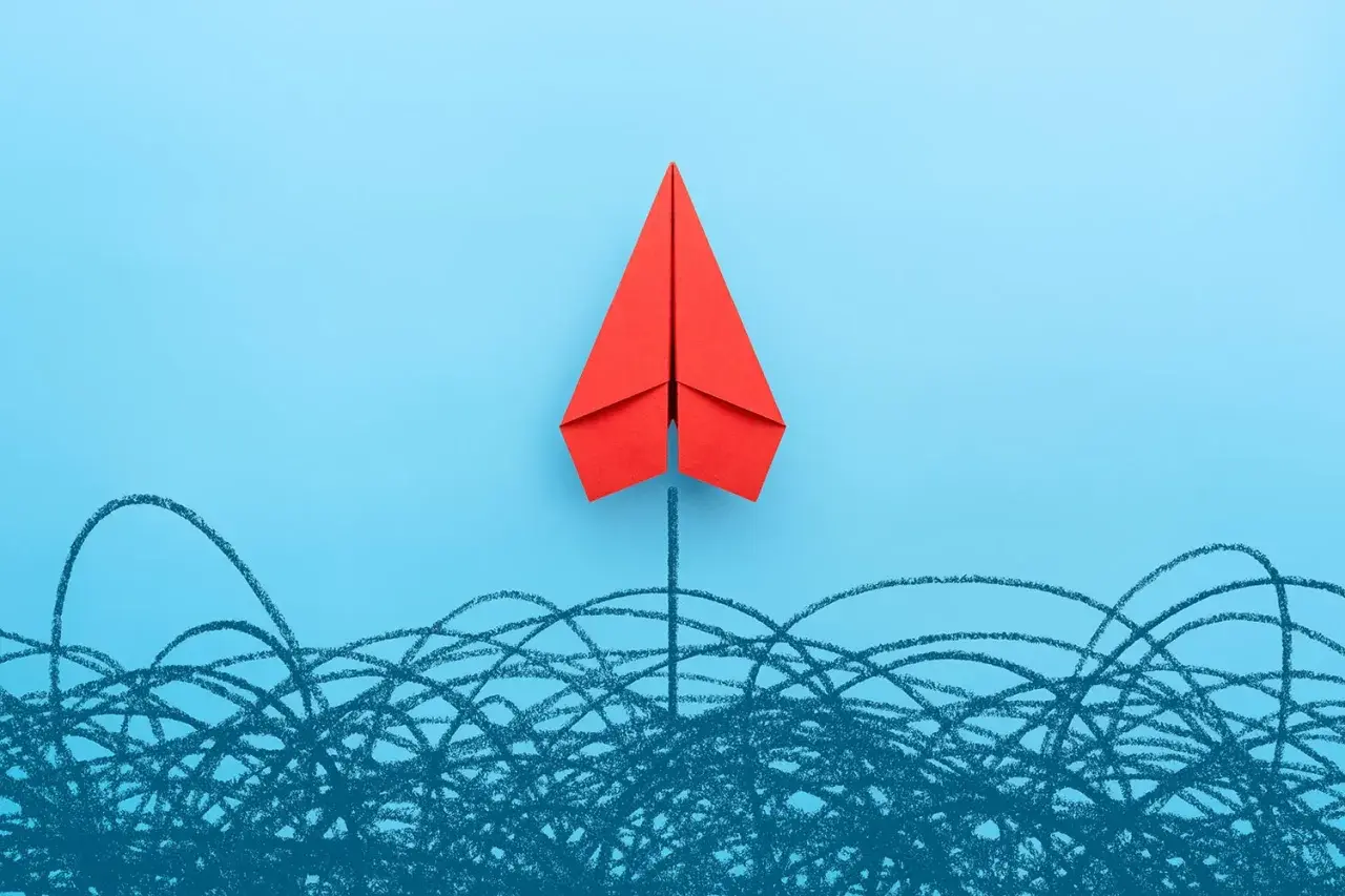 A red paper airplane soars above a chaotic scribble, symbolizing a new board of directors breaking through challenges.