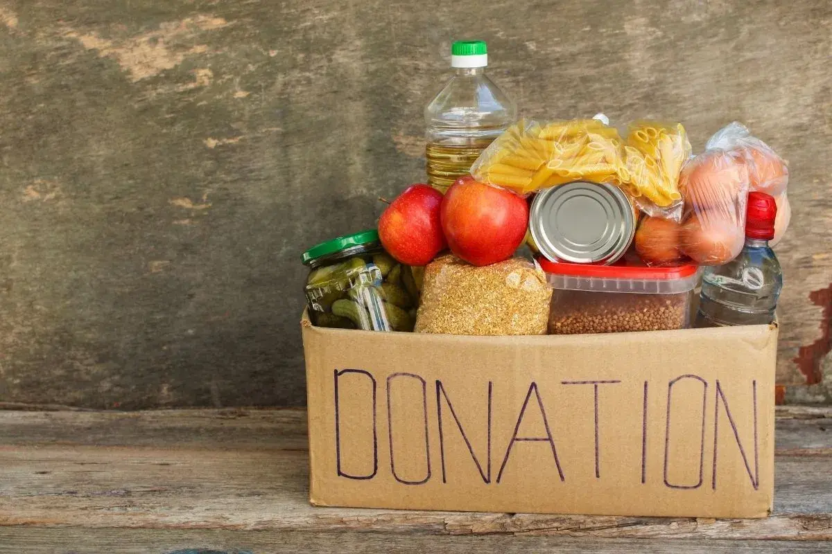 A donation box filled with food items like pasta, apples, pickles, and eggs, perfect for fundraising ideas for homeless shelters.