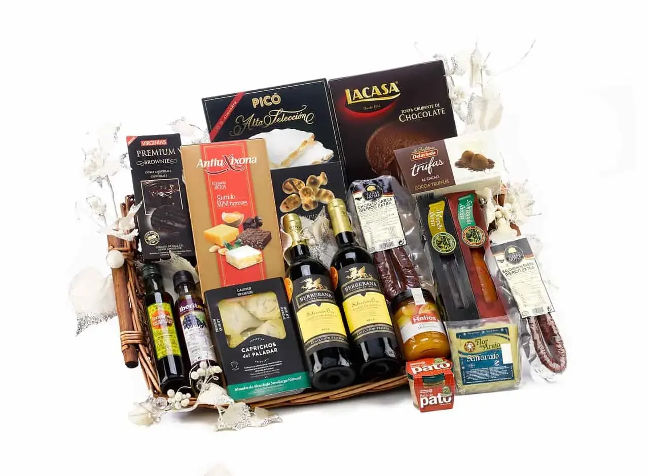 A gourmet gift basket overflowing with Spanish delicacies: wine, chocolates, turrones, olive oil, and cured meats, perfect for silent auction basket ideas.